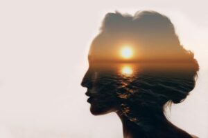 silhouette of a womans head with artistic image of ocean and sunset superimposed onto the silhouette symbolizing cognitive-behavioral therapy