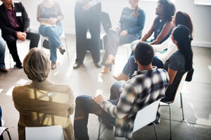 group of men and women sitting in a circle engaged in a heroin addiction treatment program