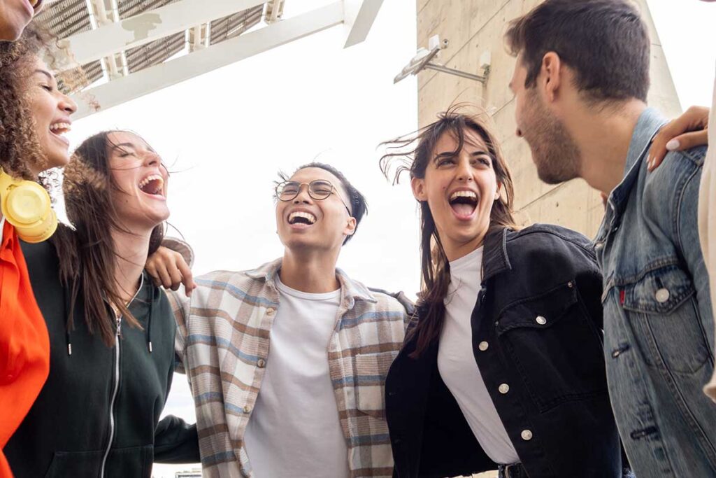 group of young men and women laughing together as they discover the difference between PHP vs IOP addiction treatment