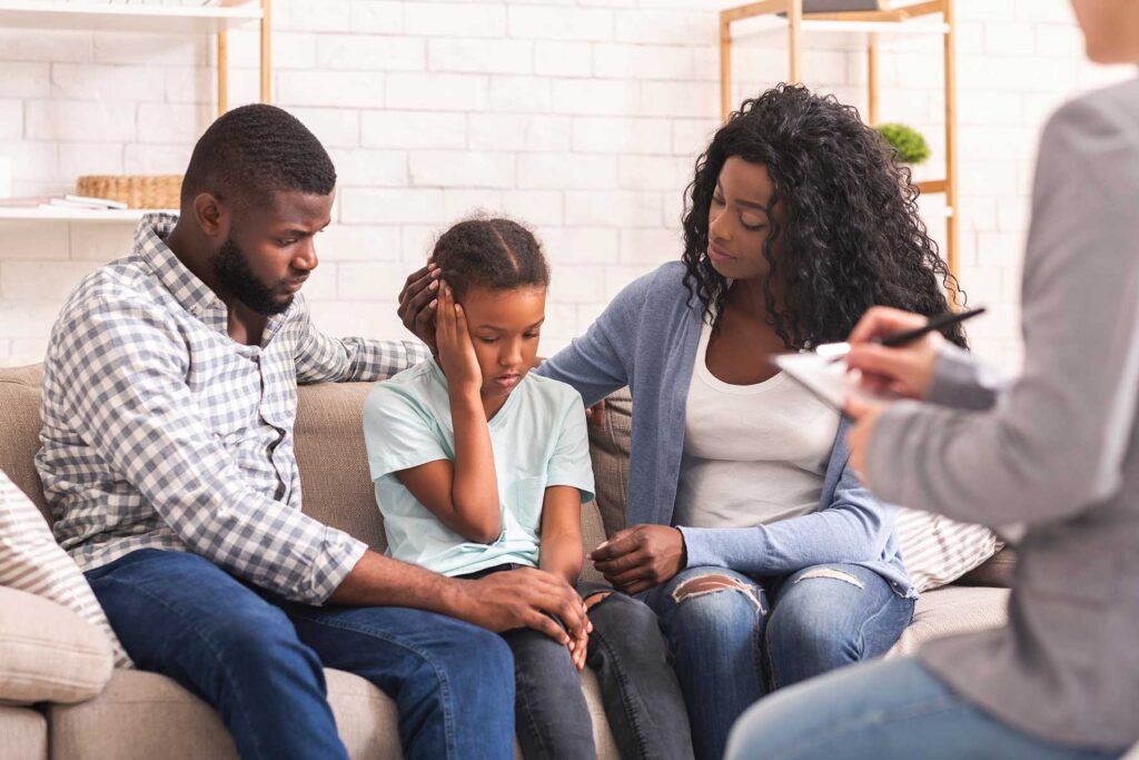 a mother, father, and young daughter are meeting with a therapist about the benefits of family counseling