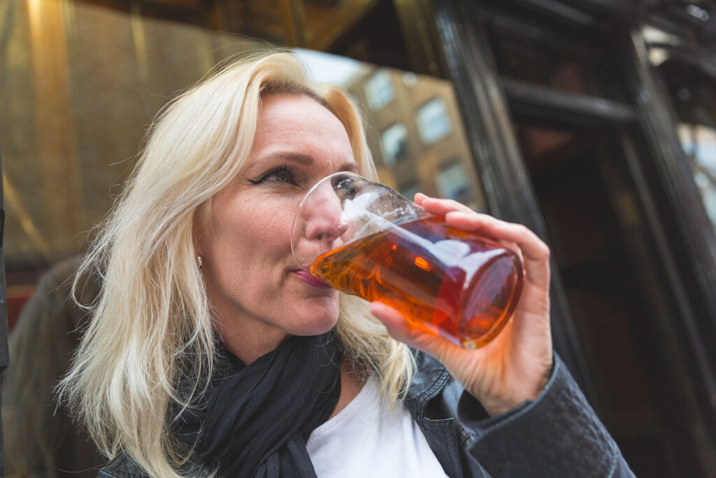 close up of woman urgently drinking a beer as an example of understanding alcohol dependence