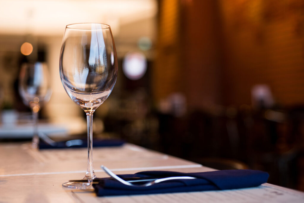 image of elegant table setting for one with an empty wine glass and empty chair symbolizing how alcohol can impact depression