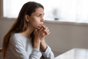 young woman seated in professional office looking pensive as she focuses on identifying relapse triggers