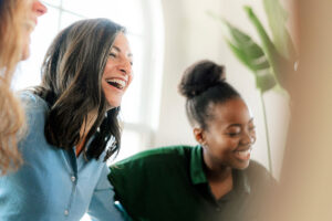 two women in a group therapy session laughing while enjoying the benefits of a gender-specific program.
