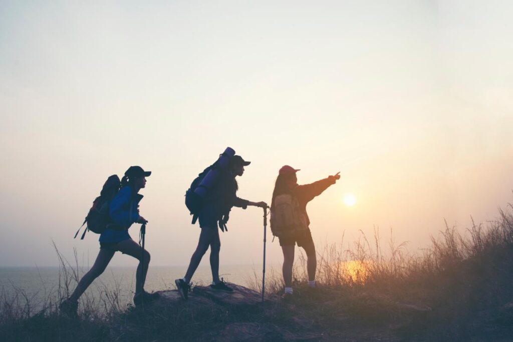 silhouette of three people hiking on a ridge at sunset and discovering what is wilderness therapy for addiction treatment.