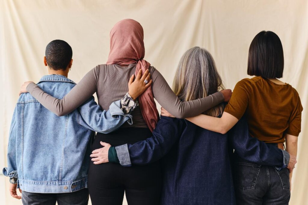 photo of a group of women taken from behind where all are standing together with arms around each other's shoulders as a result of finding a women's rehab program in North Carolina