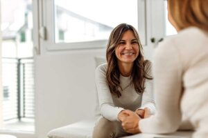 young woman smiling as she discusses the benefits of medication-assisted treatment with her behavioral health specialist.