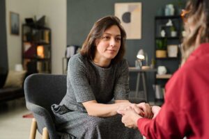 female client being greeted by behavioral health therapist in office setting to discuss what to expect in a women's rehab program.