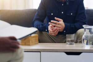 Man wringing his hands while sitting on the couch